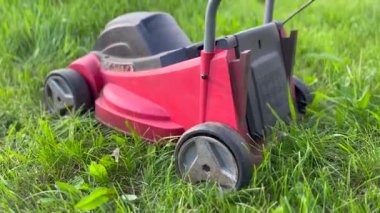 Kırmızı çim biçme makinesi yeşil çimlerde dinleniyor.