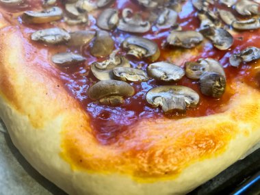 Fırında pişen mantarlı pizzanın yakın çekimi, altın kabuğu ve lezzetli malzemeler vurgulanıyor.