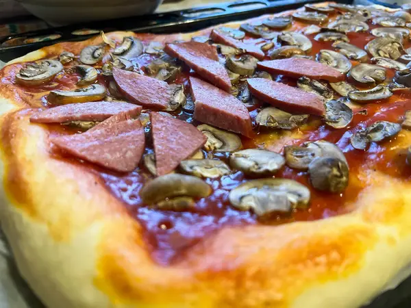 Domatesli, mantarlı, sosisli ve fırında pişirilmiş nefis ev yapımı pizza.