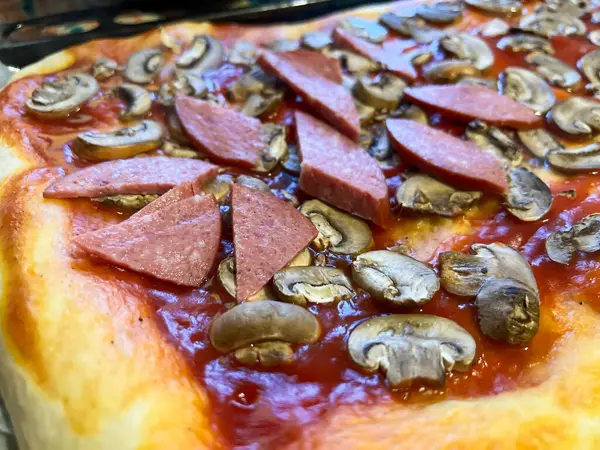 Domates soslu, mantarlı ve fırında sosisli nefis ev yapımı pizza.