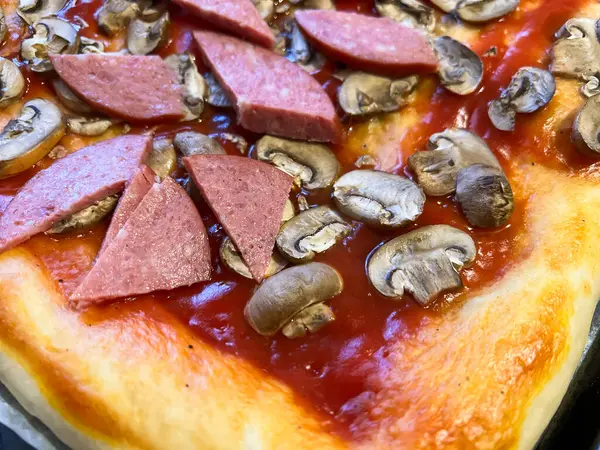 Pişmemiş, domates soslu, dilimlenmiş mantar ve sosisli, pişirmeye hazır.