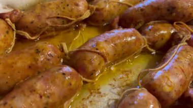 Sulu sosisler ızgara yapıyor ve kızgın bir tepside yağ salıyor.