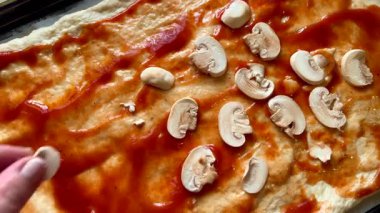 Şef pizza hamuruna doğranmış mantar ekliyor.