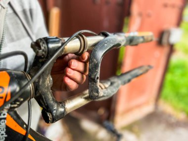 Bir dağ bisikletinin sapı ve çatalı üzerinde çalışan bir tamircinin elleri, bisiklet bakımının karmaşık detaylarını gözler önüne seriyor.