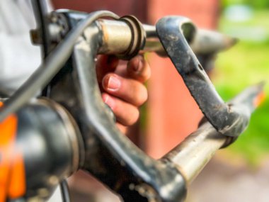 Bir dağ bisikletinin kırık gidonunu inceleyen tamircinin yakın çekimi, tamir için hasar değerlendirmesi