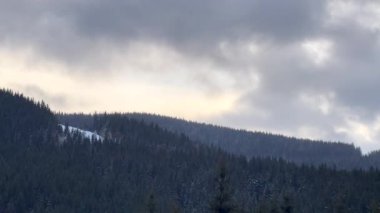 Karlı gökyüzünün altındaki yeşil dağlara büyüleyici kar yağışı