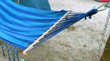 Mavi hamak bir kamp alanındaki meltemde yavaşça sallanıyor.