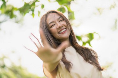 Mutlu, iyimser Asyalı kadın portresi, başarılı, çekici Asyalı kadın büyük bir gülümseme ve özgüvenle, genç sağlıklı bir kadının parkta doğal bir yaşam tarzındaki mutlu duygularının habersiz sahnesi.