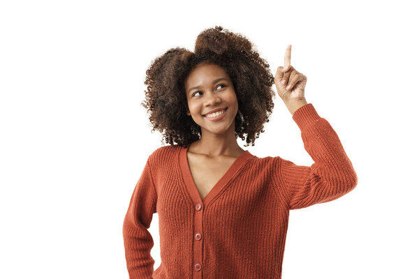 Портрет афроамериканской девушки в красном трикотажном свитере, позирующей со счастливым выражением лица и указательным пальцем вверху на белом фоне.