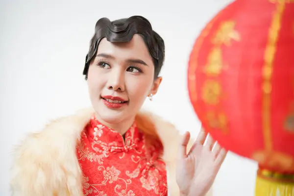 Portrait of attractive asian Chinese woman looking sideway to copy space with old vintage hair style, hold hand to touch Chinese lantern, celebrate Chinese Lunar new year season.