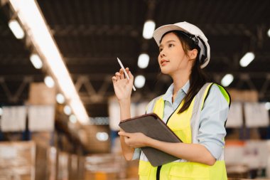 Envanter ve lojistik işleri için dağıtım deposunda çalışan Asyalı kadın depo müdürünün portresi.