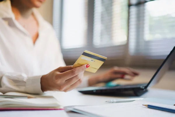 Çevrimiçi alışveriş ve online ödeme için dizüstü bilgisayar kullanırken kredi kartı tutan kadının bir kısmını vurmuş..