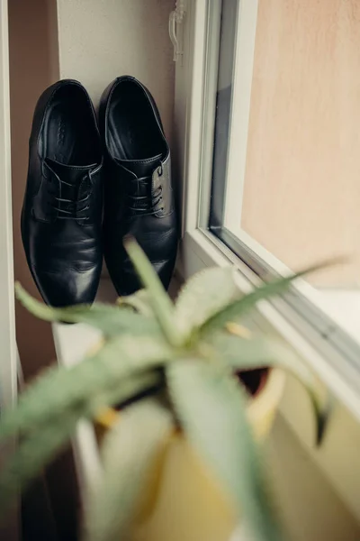 Black wedding shoes for groom next to window