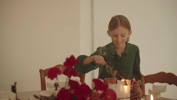 Χαριτωμένο Κορίτσι Ένα Πράσινο Φόρεμα Απολαμβάνει Βάζοντας Κεριά Των Χριστουγέννων — Αρχείο Βίντεο