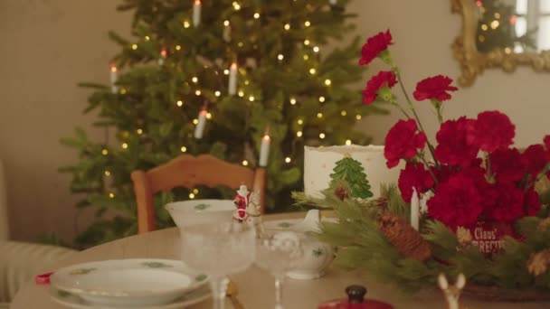 圣诞装饰桌上摆满了鲜花和圣诞蛋糕 背景上的圣诞树庆祝室内新年派对在家里 家庭晚餐 结婚的圣诞节 4K镜头 — 图库视频影像