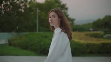 Tarz sahibi genç bir kadın sokakta tek başına yürüyor. Yan görüş açısını kapat. Üzgün yüz, beyaz gömlek, siyah saç. Yalnızlık kavramı. Yüksek kalite 4k görüntü