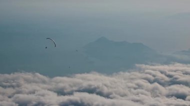 Babadak Dağı 'ndan gelen bulutların üzerinden zaman aşımına uğramış bir paraglider uçuşu. Ege Denizi Akdeniz Ege Adaları. Yüksek kalite 4k görüntü