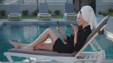 Görüntüde Happy Kafkas 'lı genç kız el hareketleriyle el kol hareketi yaparken hoşça kal diyor ve arka planda akıllı telefon kullanarak hava öpücüğü yolluyor. 4k 