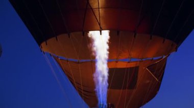 Kapadokya 'da sabahın erken saatlerinde, koyu mavi gökyüzüne karşı renkli sıcak hava balonuyla gaz yakan alevlerin yavaş çekimde yaklaşması. Yüksek kalite 4k görüntü