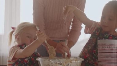 Anne ve iki kız birlikte ekmek yapıyorlar, malzemeleri karıştırıyorlar. 4 bin. Hafta sonu güneşli, ebeveynler evde, boş zamanlarımız ortak. Çocuklara geleneksel yemeklerin nasıl hazırlanacağını öğretmek. Ev yapımı ekmek..