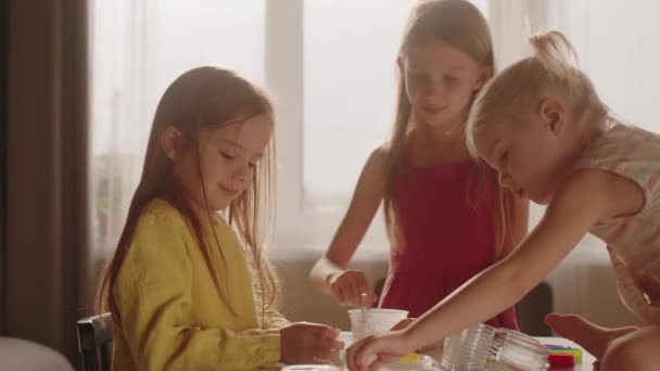 3人の女の子が一緒にスライムを作るために材料を混ぜる 化学実験 子供たちは楽しく学ぶ — ストック動画