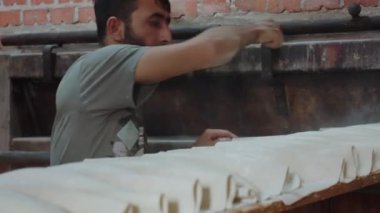Baker Ortadoğu Etkinliği, ekmeği fırına yüklemeden önce fırına un serpiyor. Ağır çekim. Gerçek bir fırında Tahsilat Günü. 4k görüntü
