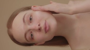 Funny happy attractive young woman applies skin care cream to her face, looks at the camera, applies moisturizing facelift cream, healthy skin care concept. 4k footage