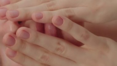 Extreme closeup feminine lips and chin applying anti aging cream on face skin. Women demonstrate moisturizing facial care touching cheek isolated in studio yellow background. 4k slow motion.
