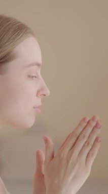 Rahatlamış genç bir kadın sabah cilt bakımını seviyor. Yüz derisini nemlendirmek için serum uyguluyorum. Sivilce önleyici tedavi, kaldırma. Güzellik, sağlıklı yaşam ve mutluluk konsepti Dikey video