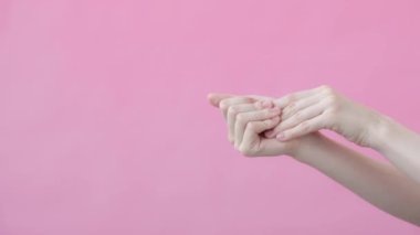 Kadın el bakımı. Eller yakın çekim, nemlendirici el kremi sürülüyor. Vücut bakımı reklamı konsepti. Pembe arkaplan Güzellik Koleksiyonu