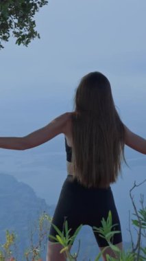 Sabah egzersizi, arka manzara, genç ince kadın, spor giyim, kol esnetme, arka planda manzaralı manzara. dikey video yavaş çekim