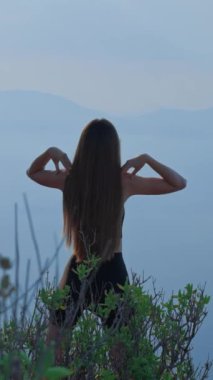 İzleme çekimi, vücut ısıtma egzersizleri yapan genç bayan arka planda manzara, sağlıklı yaşam tarzı, dikey video..