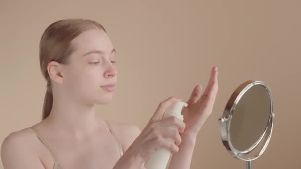 Z世代の若い女性は 彼女の顔をきれいに泡を適用します 魅力的な女性は 彼女の手の手のひらに泡を絞る ボトルを取ります 美容顔のスキンケアルーチン — ストック動画