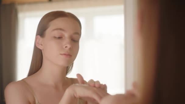 穏やかな若い女性は鏡の前で踊り ハンドクリームをこすります スキンハンドを保湿するボディケアコンセプト スローモーション — ストック動画