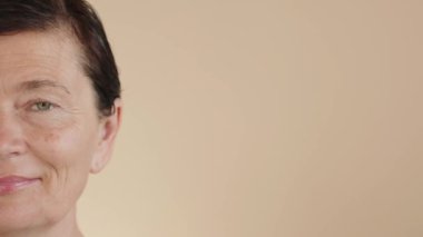 Olgun, orta yaşlı, ıslak saçlı, parlak yüzlü, mükemmel ciltli bir kadın. Reklamlar cilt bakım ürünlerini gençleştiriyor, doğal cilt bakımı için makyaj yapıyor, görme düzeltmesi yapıyor. Yakın plan. Boşluğu kopyala.