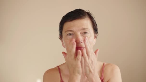 成熟女性使用润肤爽肤剂 按摩动作沿面部线条 Ph水平正常化 一位50多岁的妇女为抗衰老面部护肤产品做广告的美丽肖像 — 图库视频影像