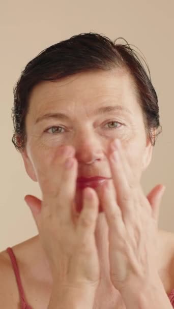 成熟女性使用润肤爽肤剂 按摩动作沿面部线条 Ph水平正常化 一个50多岁的女人的美丽的肖像广告抗老化的面部皮肤护理 垂直录像 — 图库视频影像