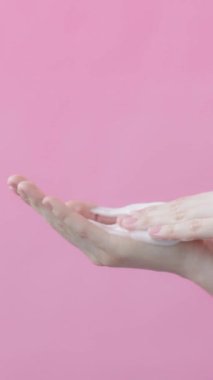 Kadın avuç içleri, köpüklü sabunları sabunlayarak dairesel hareketler yapıyor. Yüze köpük temizleme reklamı konsepti. Uzayı kopyala Pembe arka plan güzellik koleksiyonu. Dikey video