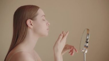 Genç bayan 20 'li yaşlarda güneş kremi sürüyor. Beyaz kadın makyaj yapmadan önce fondöten kremi sürüyor. Kadın nemlendirici, CC kremi, BB kremi sür. Günlük cilt bakımı. Kozmetik reklam konsepti