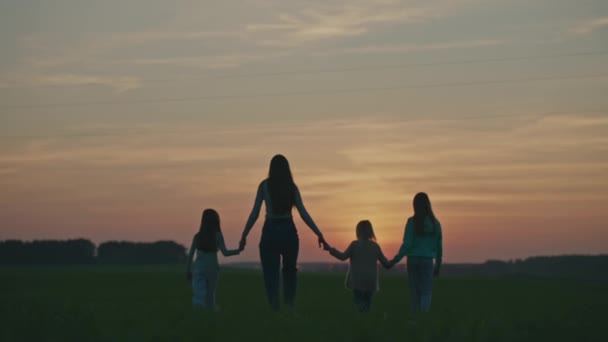 ハッピーファミリー 日没時の柔らかいフォーカスシルエット 手を握って歩くママと子供たち バックグラウンドで街灯が点灯します 家族関係 つながり 思いやり 子供時代の概念 — ストック動画
