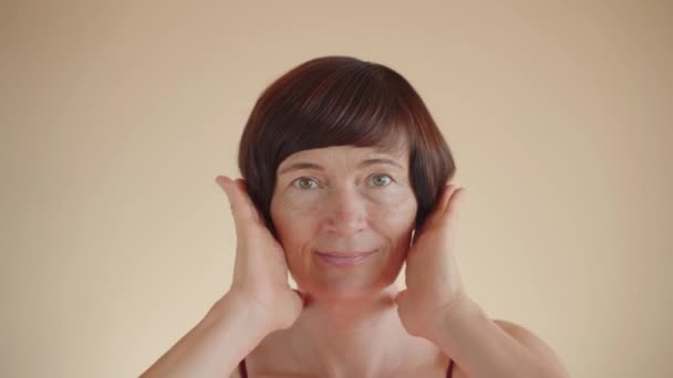 快乐地笑着 成熟的50多岁的中年妇女 动人的头发 看着相机 美丽的中年妇女 拥有丰满的发型 抗老化的洗发水 适合健康的头发护理 — 图库视频影像
