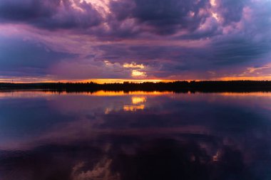 Finlandiya 'da Rovaniemi nehrinde çok renkli, karanlık bir gün batımı. Kutup günü. Laponya manzarası. Suda yansıma. Suomi. Kuzeye git. Kuzey güzelliği, Kuzey Kutup Dairesi 'ne gidiyor. 