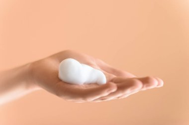 Aşırı yakın plan, dişi avuç içi köpüklü ve izole şeftali arkaplan. Yüz temizleyici.