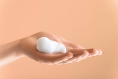 Aşırı yakın plan, dişi avuç içi köpüklü ve izole şeftali arkaplan. Yüz temizleyici.