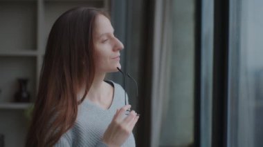 Gözlüklü, uzun esmer, çekici beyaz bir kadının portresi derin bir nefes alır ve stresi azaltır. Zihinsel rahatlama egzersizleri yaparken sessiz bir anın tadını çıkarır, yan profil görünümü