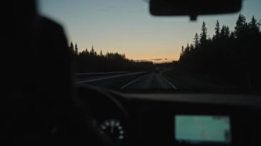 Arabanın içini görmek, şoförün kahve içmesi manzaralı bir çam ormanı yaz yolunda bir seyir subayıyla araba kullanması. Günbatımında İskandinav yolculuğu, Kuzey Finlandiya 'da Laponya' nın doğası, kırsal bölge. 