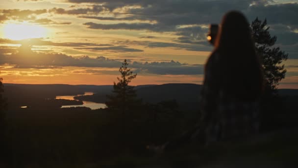 フィンランド ロヴァニエミ サンタヴァラ丘の上のキングスから見た壮大な景色 電話のある女性のシルエット 夏の夕方に素晴らしい夕日がやってきました ハイキング ラップランドの観光スポット — ストック動画