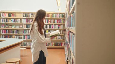 Kütüphanede veya kitapçıda kitap karıştıran tanınmamış esmer, sınav hazırlığı, öğretmenlik eğitimi, yüksek öğrenim, öğrenciler için e-öğrenim, yüksek lisans, bekarlar, stajyerler için araştırma projesi