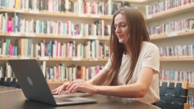 Kafkas kadın esmer öğrenci kütüphanede makaleler yazıyor, üniversite ödevi, sınava hazırlık, internet sohbeti, kadınlar için yüksek öğrenim, öğretmenlik e-öğrenimi, iş projesi 