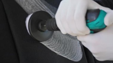 Profesyonel araba temizliği. İşçi, araba koltuğu döşemesini temizlemek için profesyonel fırça kullanıyor. Profesyonel araba tamiri reklamı. Yavaş çekim.